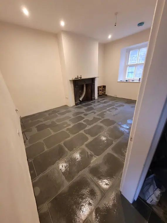 The flagstone floor sealed and finished, with the cast-iron fireplace at the end of the room.