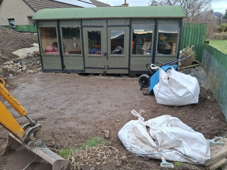 Bare, compacted ground around a sun room before landscaping