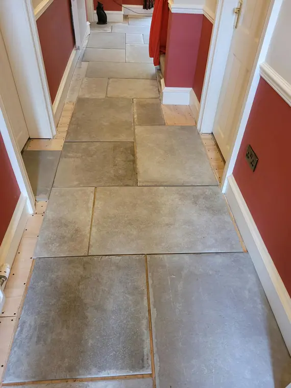 Large-format stone-effect tiles laid down the full length of the hall in a random pattern.