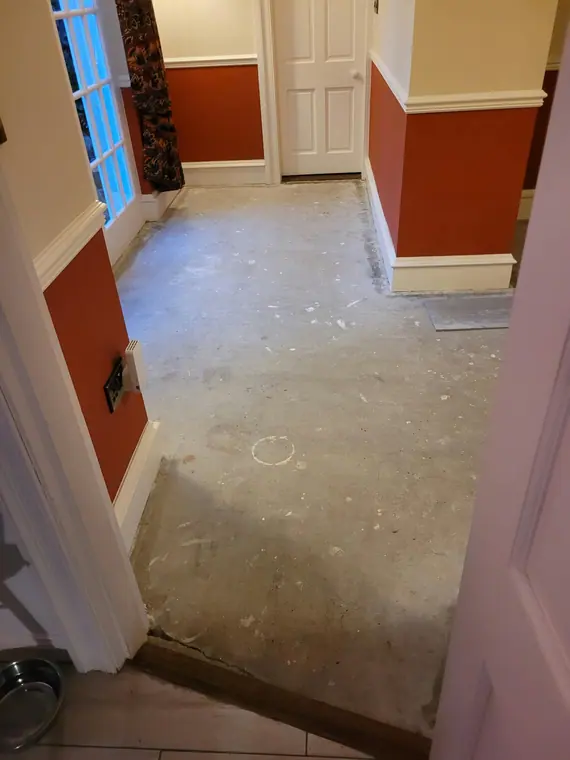A hallway stripped to bare screed before tiling