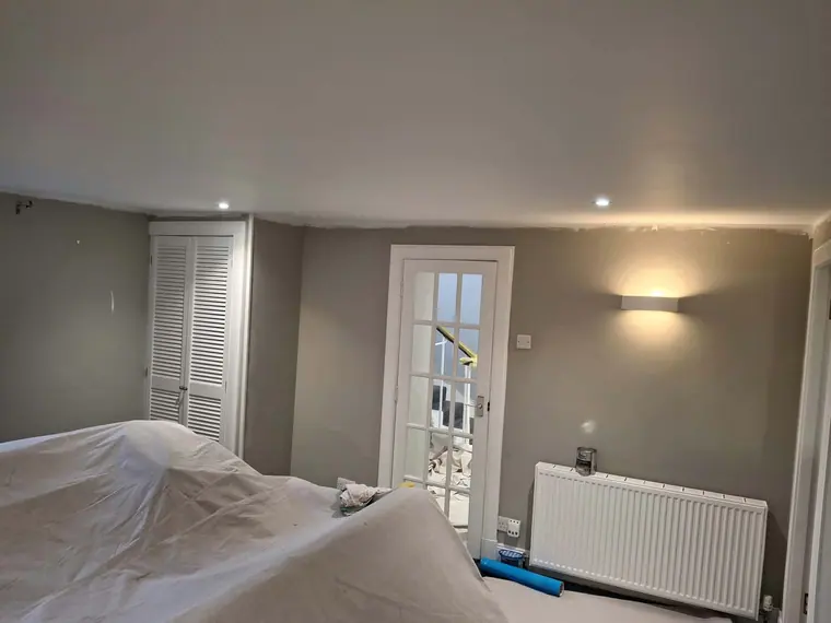 Walls painted in warm grey with the furniture still under dust sheets.