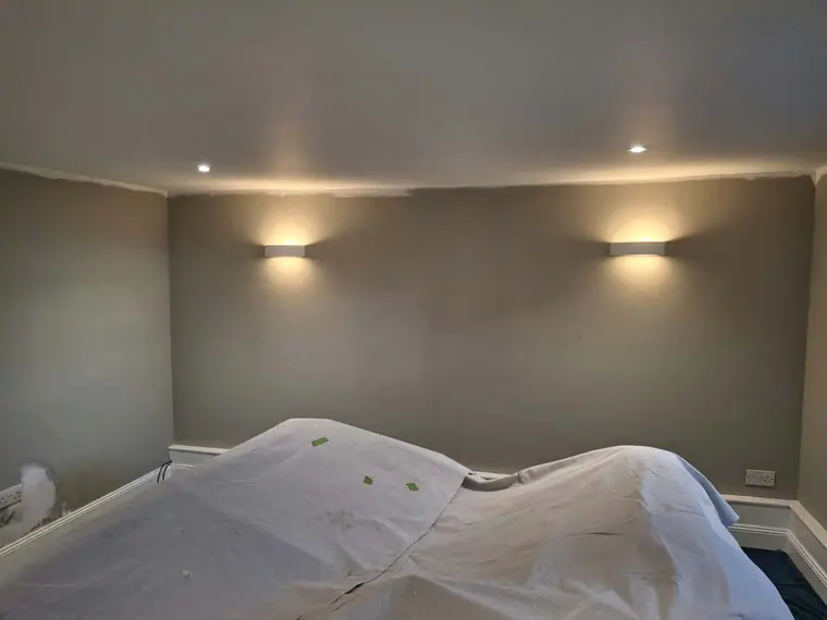 Walls done around the wall lights, the sofa still sheeted.