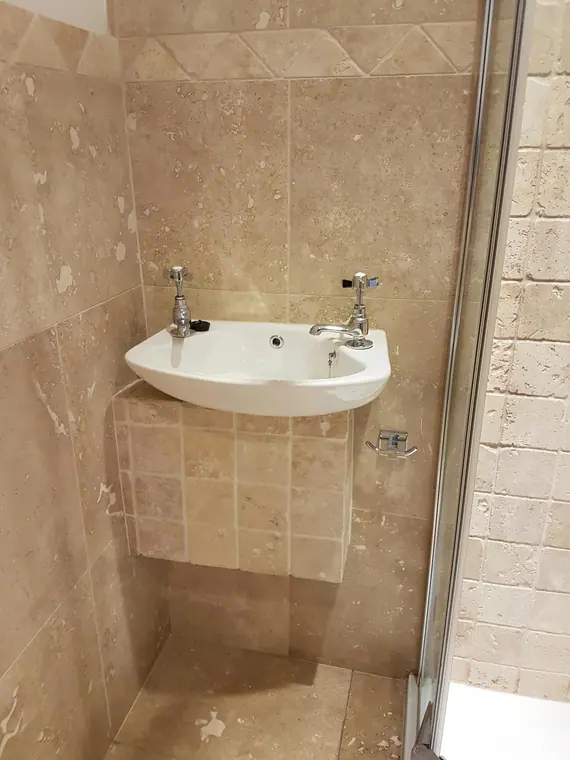 The corner basin on its tiled plinth, finished neatly against the shower screen.