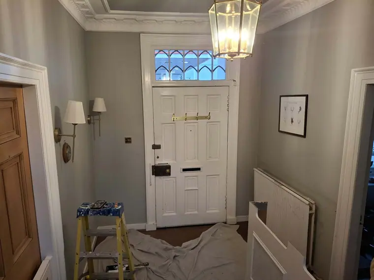 The entrance hall part-way through: front door refinished, walls painted, dust sheets still down.