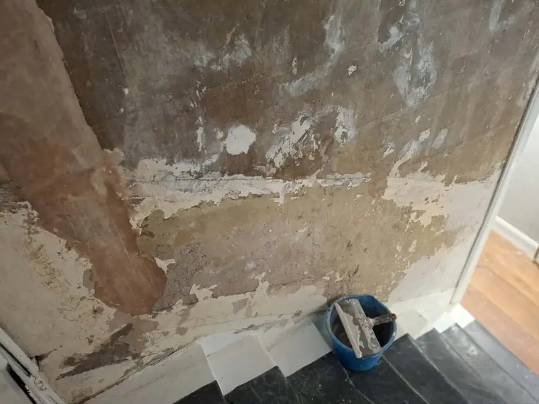 A wall taken back to bare plaster so the repairs could be done properly before any paint went on.