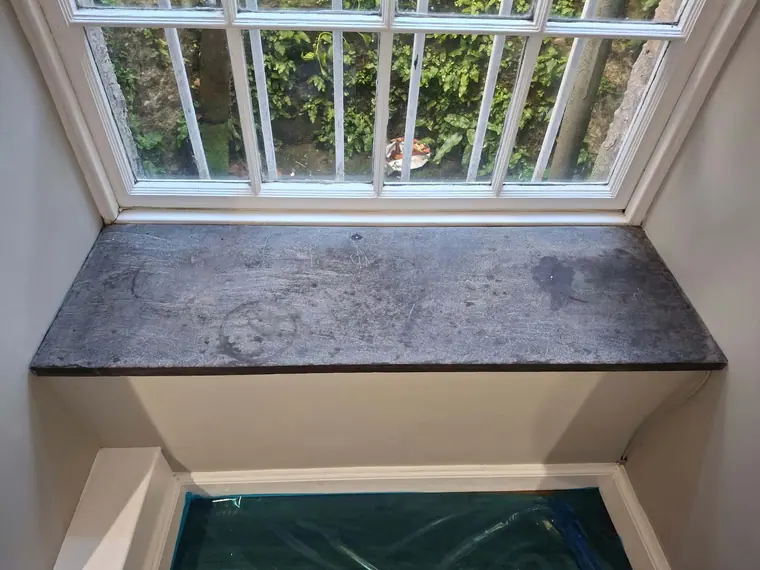 A worn and stained window board before restoration